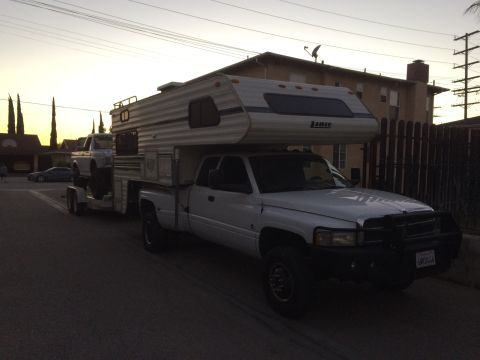1997 Dodge 3500 - Dodge pickup truck with camper shell and trailer carrying another truck at dusk.