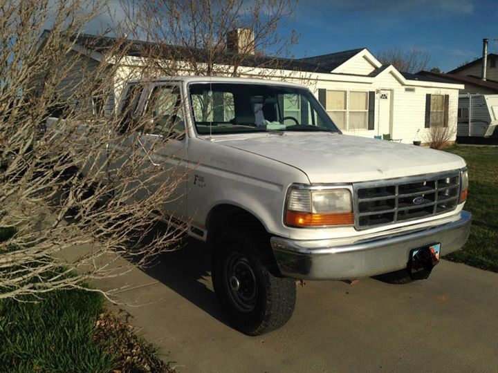 White Ford F-250 parked in front of a house. Front end and driver's side are visible