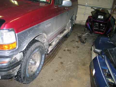 1995 Ford Bronco - A red and silver Ford Bronco is parked in a garage next to a snowmobile and another vehicle.