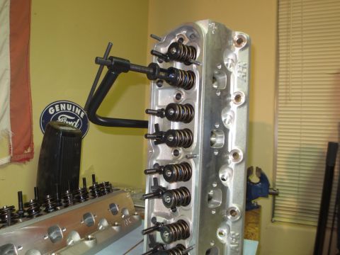 1996 Ford Bronco - Two aluminum engine cylinder heads are shown, one in the foreground and another in the background, with a "Genuine Ford" logo on the wall.