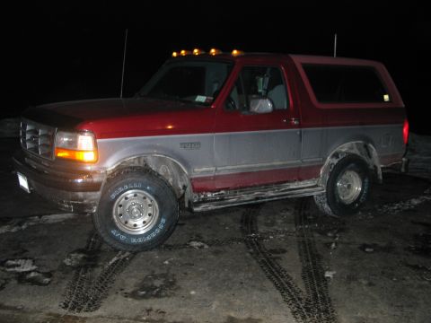 1995 Ford Bronco - This two-tone Ford Bronco, likely from the early to mid-1990s, is shown from a three-quarter front angle at night.