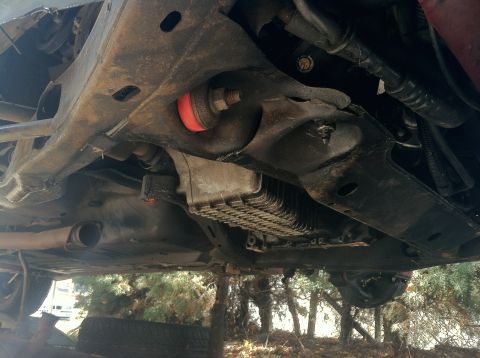 1993 Ford Taurus - The undercarriage of a car shows red suspension bushings and a ribbed oil pan, suggesting an older model.