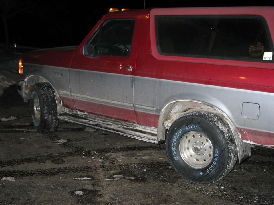 Red and silver Ford Bronco at night, salt-crusted rockers, Pirelli Scorpion A/T tires