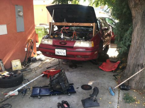 1993 Ford Taurus - This red sedan is undergoing engine and transmission work in a driveway.