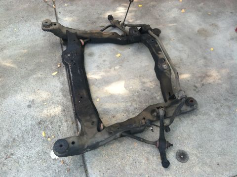 1993 Ford Taurus - A removed subframe assembly, likely from the front suspension of a car, lies on a concrete surface.