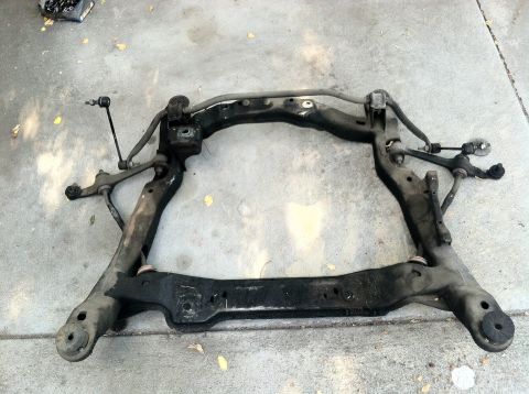 1993 Ford Taurus - A disassembled vehicle subframe assembly rests on a concrete surface, showing suspension linkages.