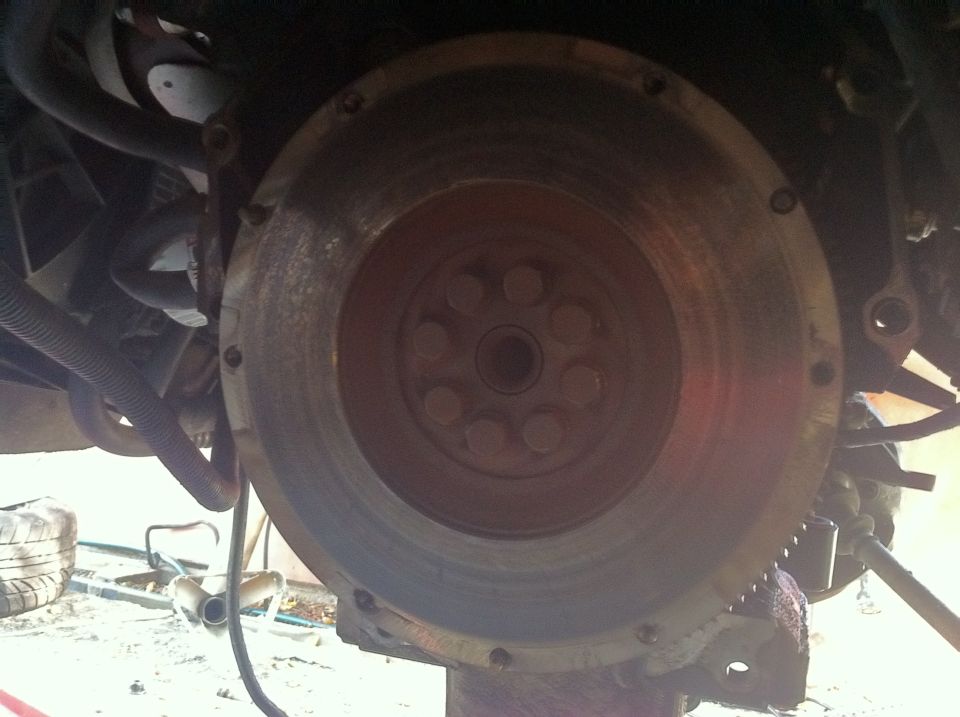 Close-up of a vehicle's flywheel and clutch assembly, showing bolted connections