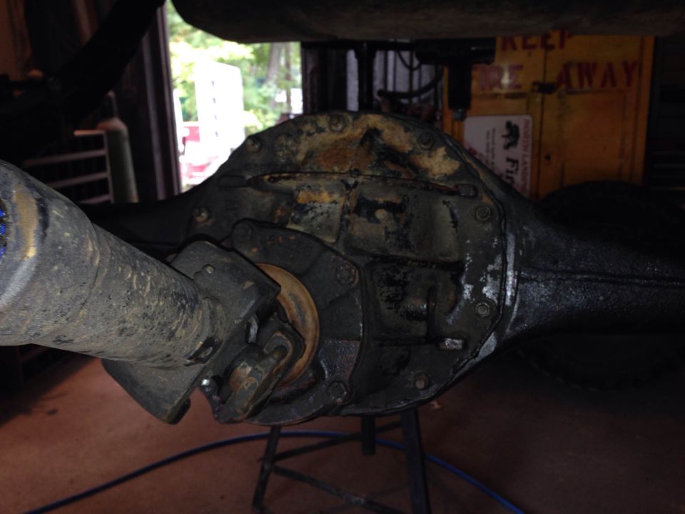 close-up of a rear axle differential with driveshaft attached, in a garage setting