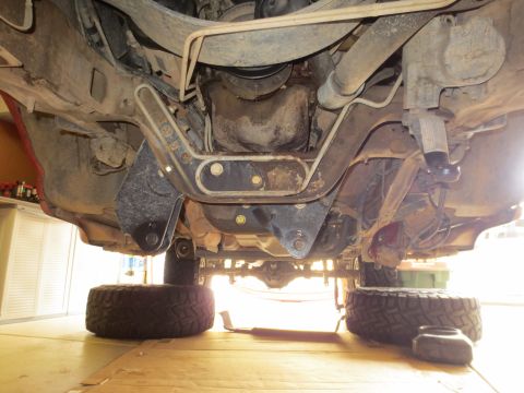 1996 Ford Bronco - The underside of a vehicle, likely a 1996 Ford Bronco, is shown with its suspension and drivetrain components visible. The vehicle is suppo…