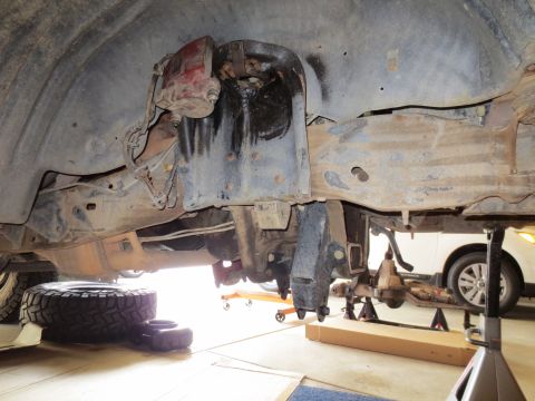 1996 Ford Bronco - The underside of a 1996 Ford Bronco is shown with the front suspension components removed and the vehicle supported by jack stands. A tire…