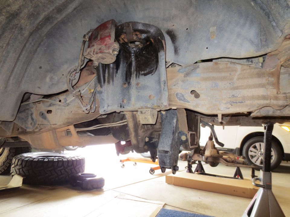 Underside of a 1996 Ford Bronco with suspension removed, supported by jack stands.