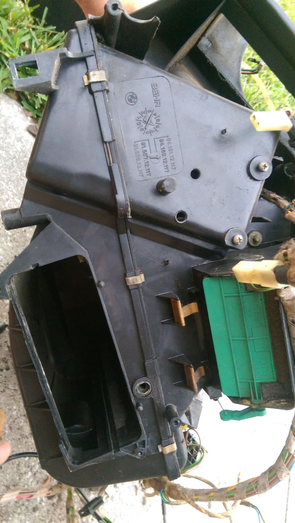 Black plastic HVAC blower motor housing with green filter and wiring harness