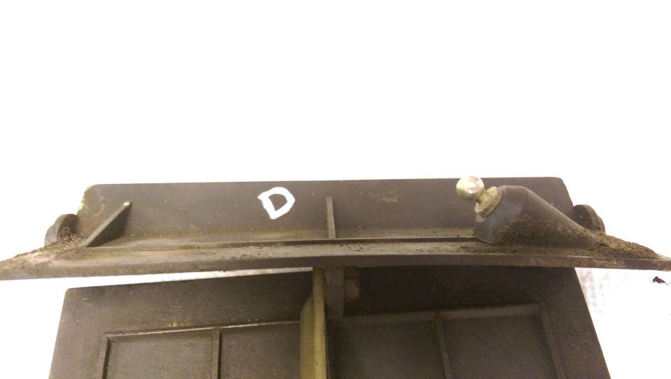 Close-up of a dark gray plastic HVAC part with a white 'D' and a ball-joint actuator.