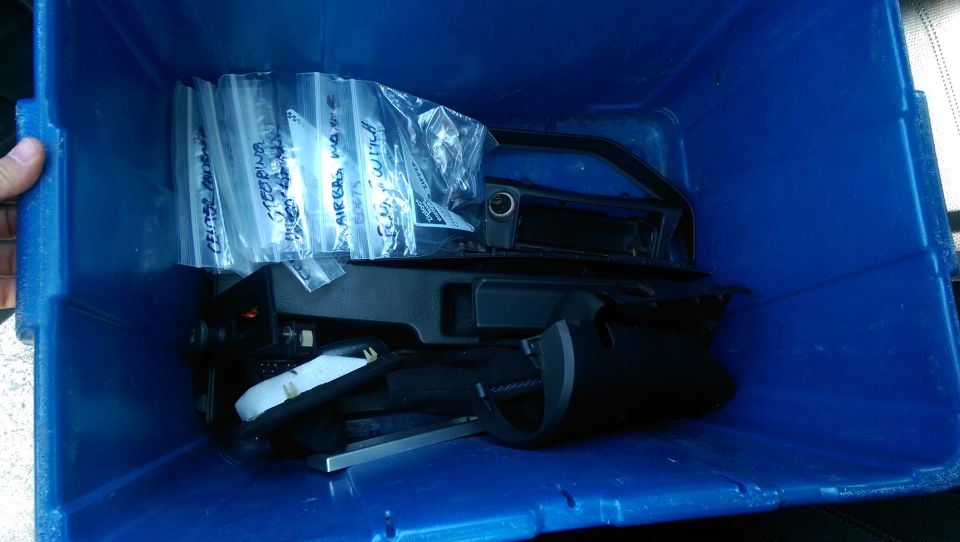 Blue bin with bagged car parts including steering and airbag modules.