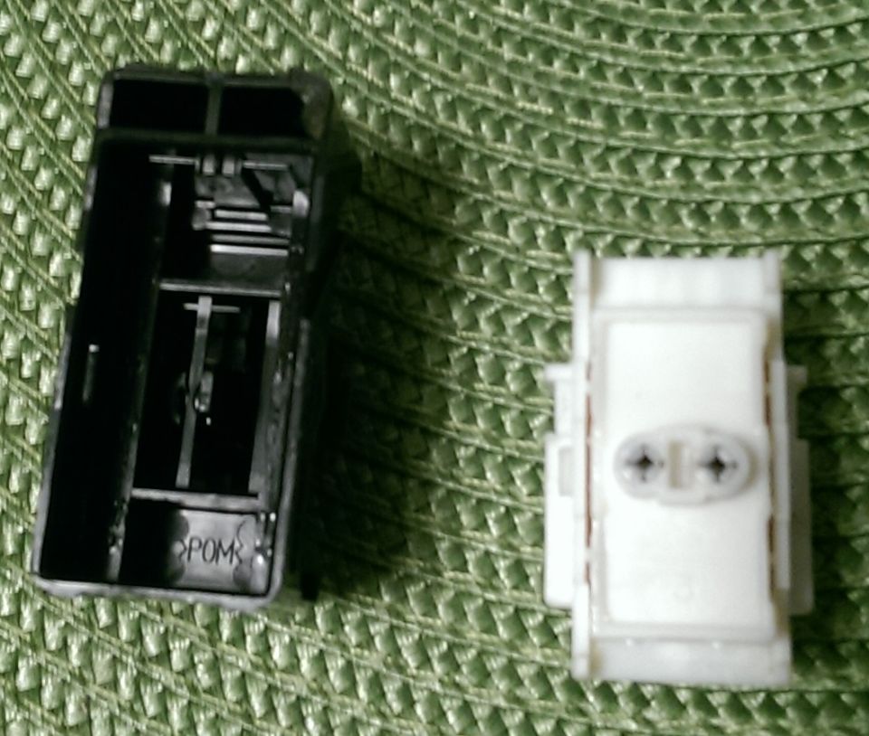 Black and white plastic automotive parts on a green textured background.