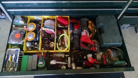 1994 Ford Bronco - This image shows an open toolbox drawer filled with various power tools and sanding supplies. Visible items include a reciprocating saw, or…