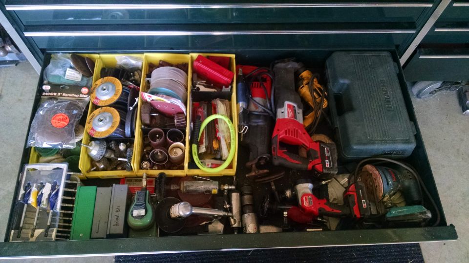 Toolbox drawer filled with power tools and sanding supplies.