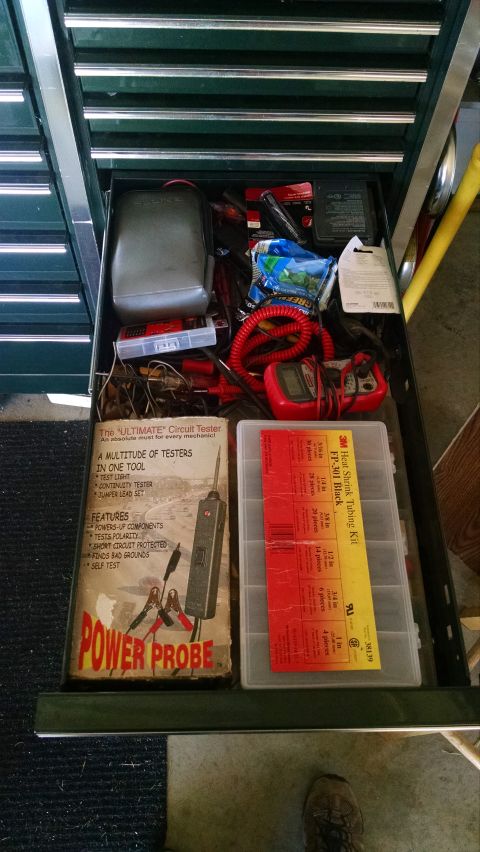 1994 Ford Bronco - An open drawer in a dark green toolbox is filled with various automotive tools and supplies. Visible items include a circuit tester, a mult…