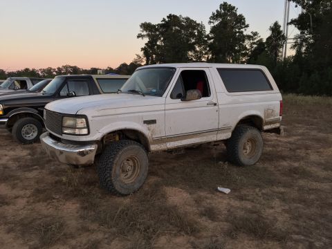 1996 Ford Bronco - A white, lifted Ford Bronco is parked on a dirt lot with other vehicles behind it. The vehicle is covered in mud, suggesting it has been us…