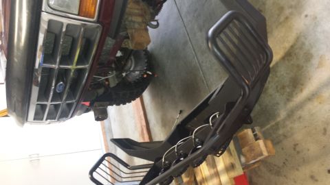 1996 Ford Bronco - A black aftermarket brush guard is mounted to the front of a dark red 1990s Ford Bronco. The vehicle's grille and headlight are visible, al…