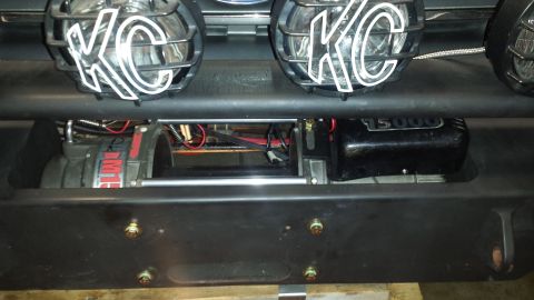 1996 Ford Bronco - A close-up view of a winch and KC lights mounted on the front of a vehicle. The winch is labeled "DM15" and appears to be a 15,000 lb capac…