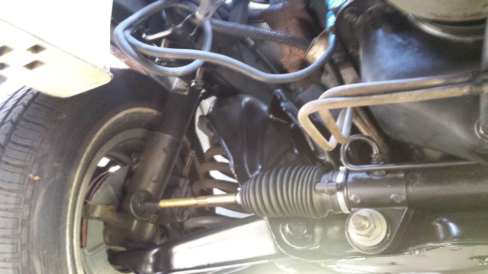 Close-up of vehicle front suspension and steering rack with tire.
