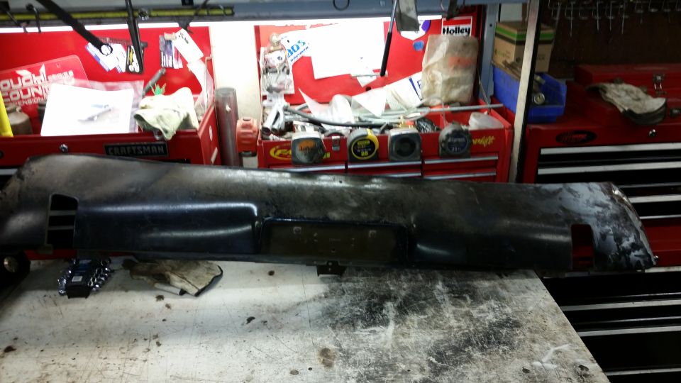 Black vehicle bumper panel with license plate cutout on workbench