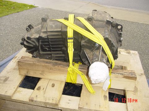 1987 Ford Bronco - Transmission assembly on a wooden pallet, secured with yellow straps.