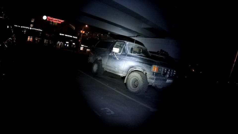 1987 Ford Bronco parked under an overpass at night.