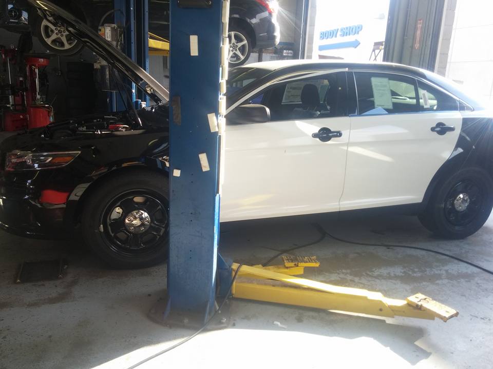 White and black sedans inside an automotive repair shop