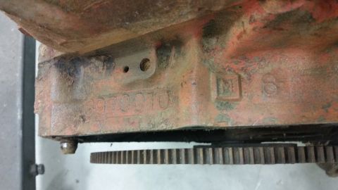 2015 Chevrolet new - A close-up view of an orange engine block with stamped numbers and letters. A toothed gear is visible at the bottom of the engine block.