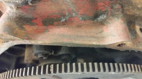2015 Chevrolet new - A close-up view shows the teeth of a flywheel or flexplate, with a portion of a red engine block visible above it. The engine block appears…