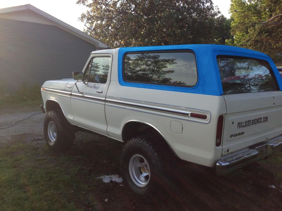 White lifted Ford Bronco with blue soft top, rear 3/4 view, text FULLSIZEBRONCO.COM on tailgate.