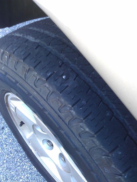 1994 Ford Bronco - A nail is embedded in the tread of a vehicle tire.