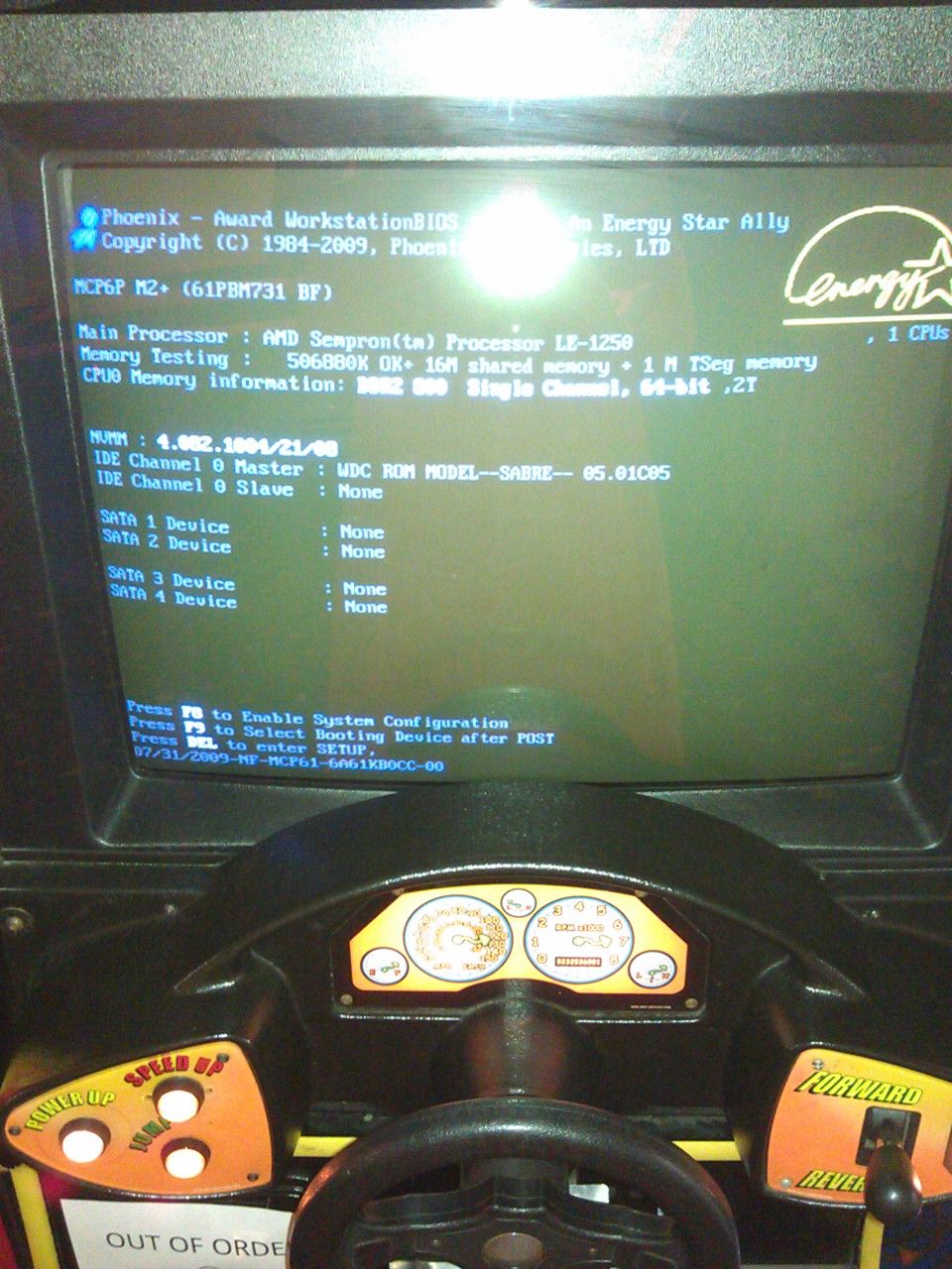 Arcade game screen showing Phoenix-Award BIOS and a steering wheel with gauges. Copyright 1984-2009