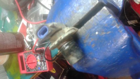 1996 Ford Bronco - A close-up view of an automotive sensor clamped in a vise, with a multimeter visible in the background.