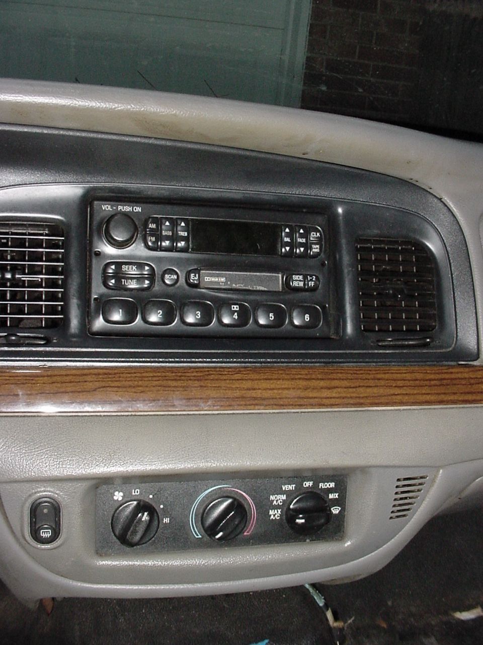 Car dashboard with radio, climate controls, and wood trim