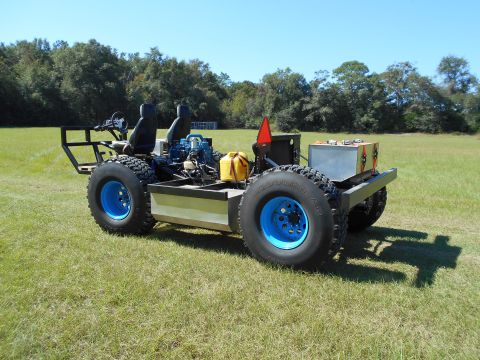 1992 Ford Bronco - Custom off-road vehicle with two seats and large tires sits in a field under a clear blue sky.