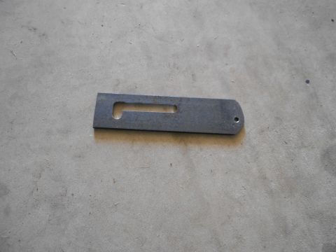 1992 Ford Bronco - A metal bracket with a slot and a hole is shown on a concrete floor.
