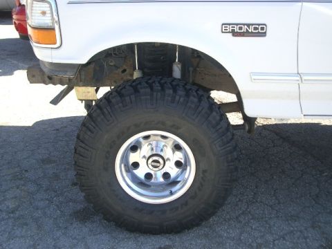 1994 Ford Bronco - A white 1994 Ford Bronco is shown from the front 3/4 view, highlighting its large off-road tires and "BRONCO" badging.