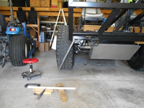 1992 Ford Bronco - A partially assembled vehicle frame with large tires and interior seats is visible in a garage setting.
