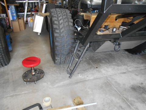 1992 Ford Bronco - A heavily modified truck chassis is shown in a garage with large tires and custom steps.