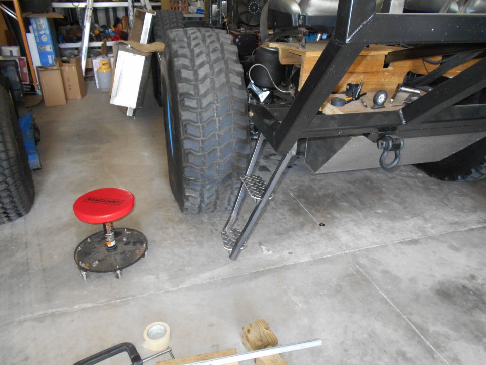 Truck chassis with large tires, metal steps, and a tow hitch