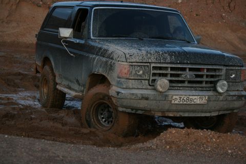 1987 Ford Bronco - This 1987 Ford Bronco navigates a muddy off-road course, showing its capabilities.