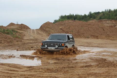 1987 Ford Bronco - 1987 Ford Bronco navigating a muddy obstacle course in a dirt quarry.