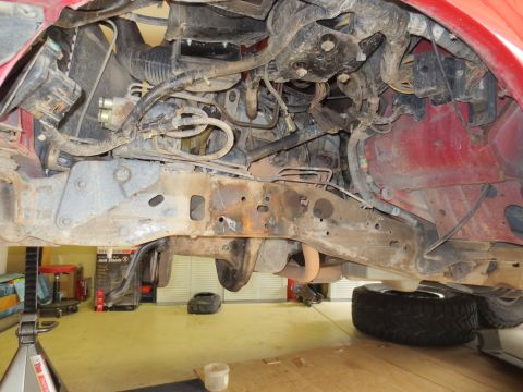 1996 Ford Bronco - Undercarriage view of a red vehicle, showing the frame and engine components.