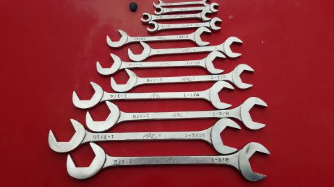 1965 Ford Mustang - A collection of MAC brand combination wrenches are neatly arranged on a red background.