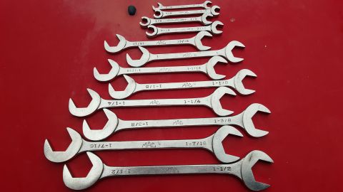 1965 Ford Mustang - A collection of MAC brand combination wrenches laid out on a red surface.