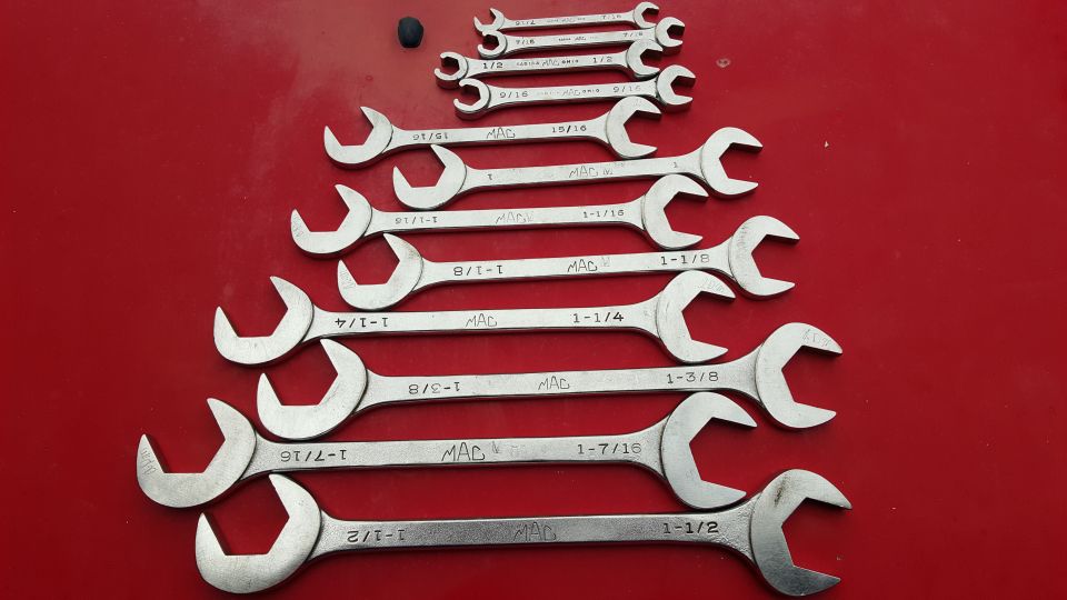 Set of MAC combination wrenches on a red surface, various sizes visible