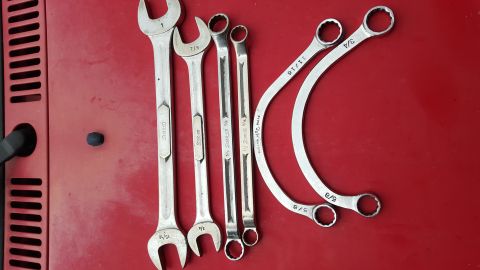 1965 Ford Mustang - A collection of various wrenches, including some specialized curved ones, are arranged on a red background.
